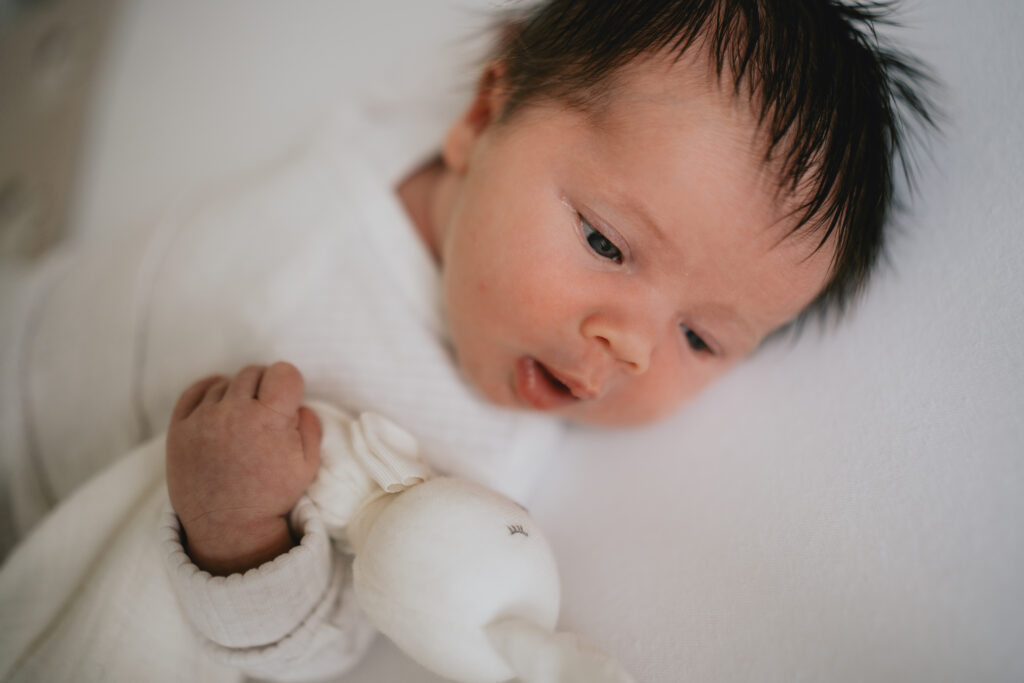 newborn baby holding toy