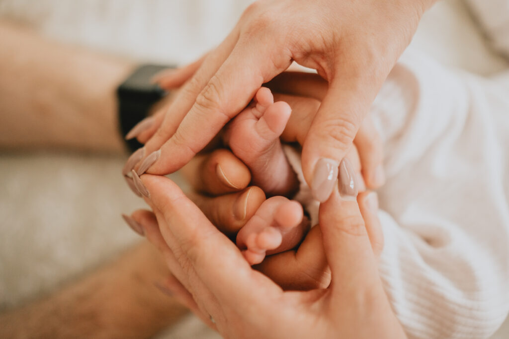 newborn baby with mum and dad holding feet